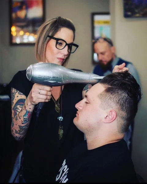 Tami Lee finishing a men's haircut with a blowdry